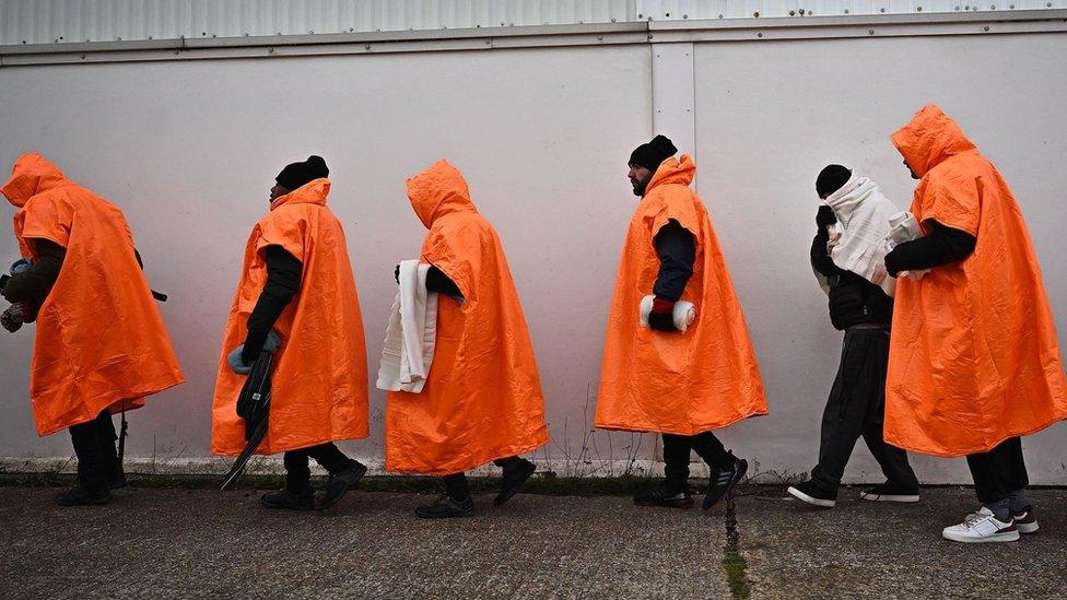 Migrants standing in a queue waiting to be processed in Kent.