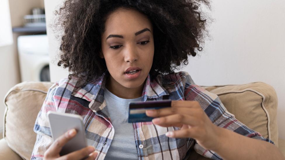 Worried woman with a bank card and phone