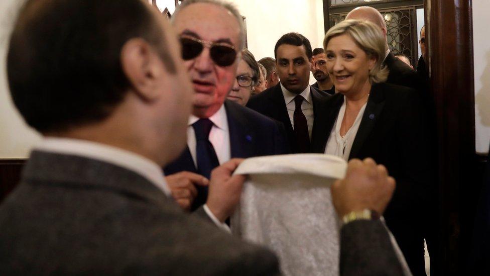 An aide of Lebanon's Grand Mufti Sheikh Abdel-Latif Derian, left, gives a head scarf to French far-right presidential candidate Marine Le Pen, right, to wear during her meeting with the Mufti but she refused, upon her arrival at Dar al-Fatwa the headquarters of the Sunni Mufti, in Beirut, Lebanon, Tuesday, 21 Feb, 2017