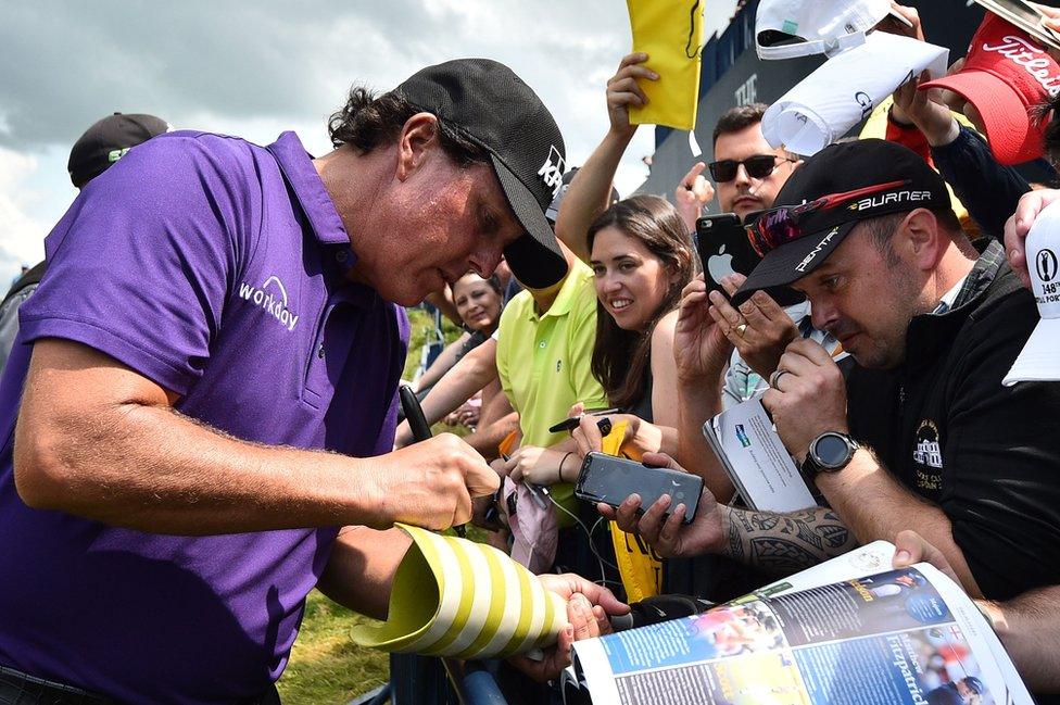 Fans look on as Phil Mickelson signs a prostehtic leg at Royal Portrush