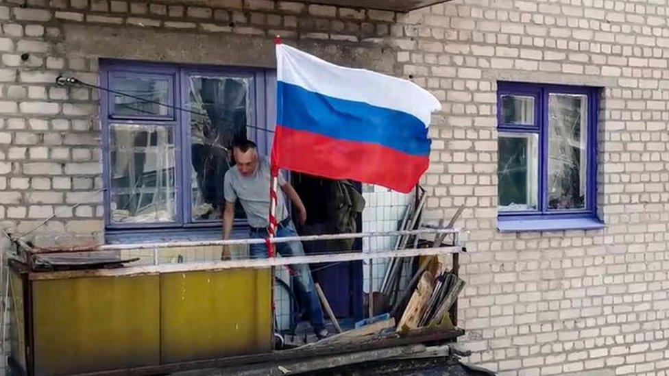 Image shows Russian flag waving from balcony