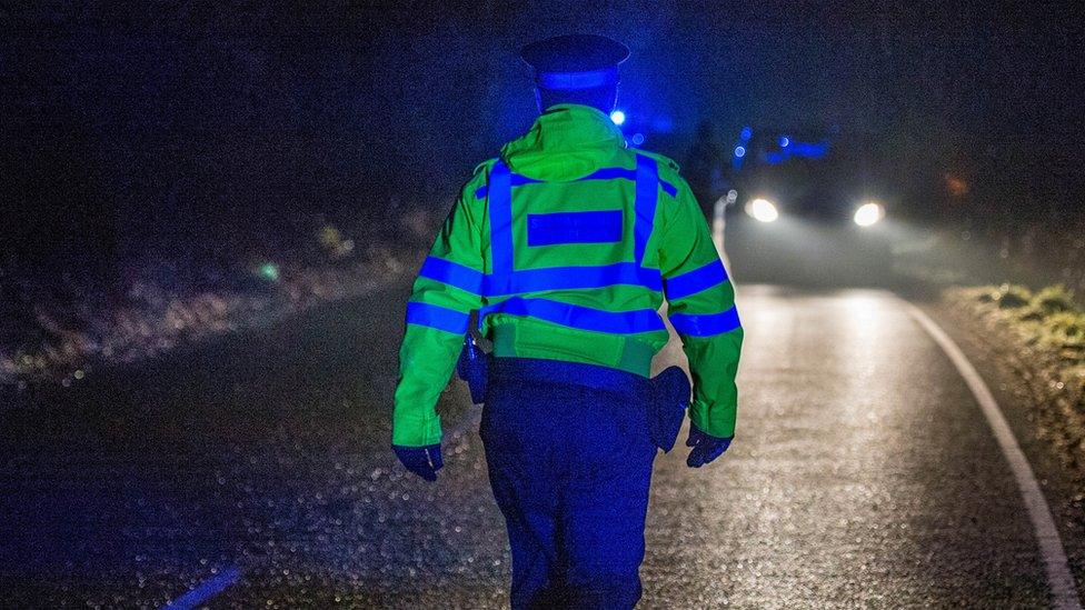 A police officer walking towards a car