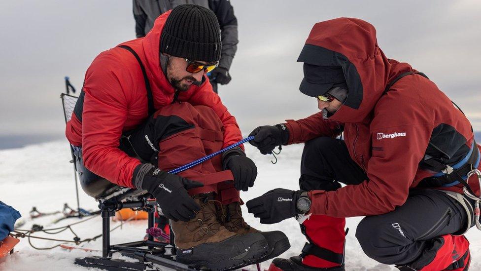 Niall McCann helping to strap Darren Edwards into his ski seat