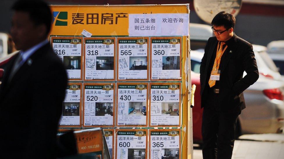 A man looking at a property advertising board in Beijing