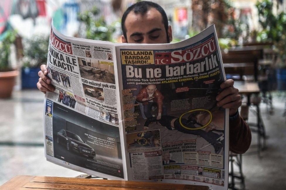 A man reads a newspaper with a headline concerning diplomatic tensions between Turkey and The Netherlands, which translates as "What a Barbarism" in Istanbul on 13 March, 2017