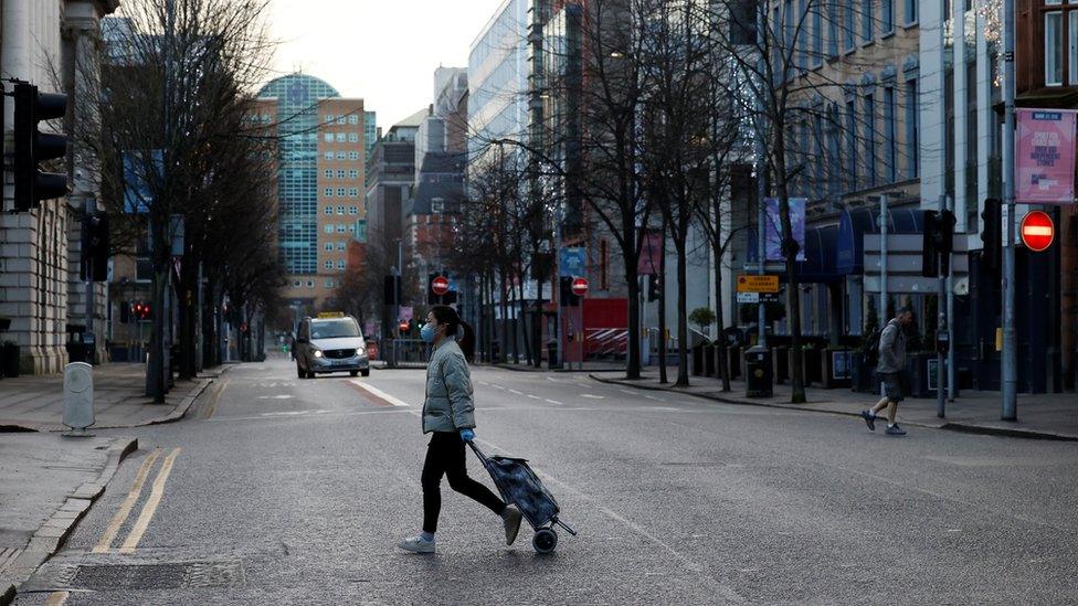 A woman walks across a deserted street in Belfast city centre