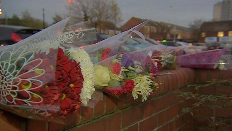 Bunches of flowers laid out in a row on a red brick wall