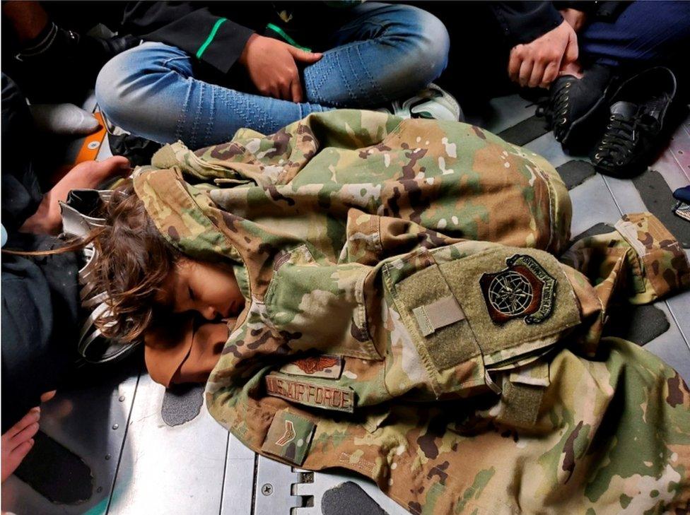 An Afghan child sleeps on the floor of a US Air Force plane during an evacuation flight from Kabul