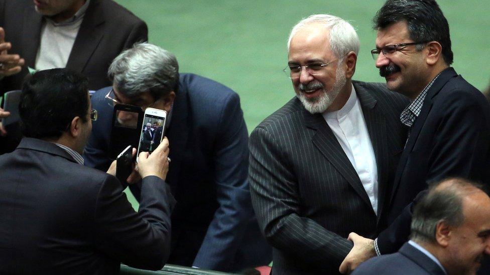 Iranian Foreign Minister Mohammad Javad Zarif is greeted by colleagues on the floor of the Iranian parliament