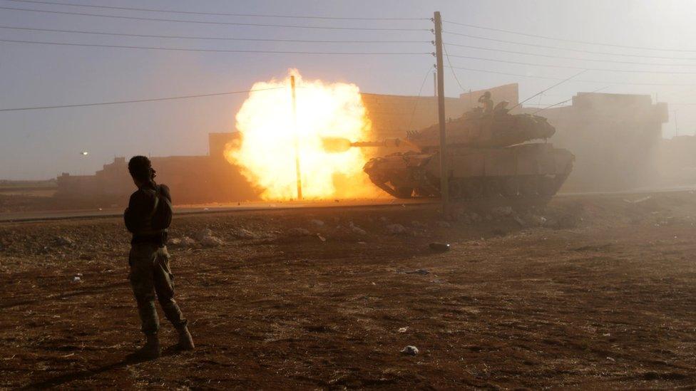 A rebel fighter stands near a Turkish tank as it fires towards Guzhe village, in the northern Aleppo countryside, Syria (17 October 2016)