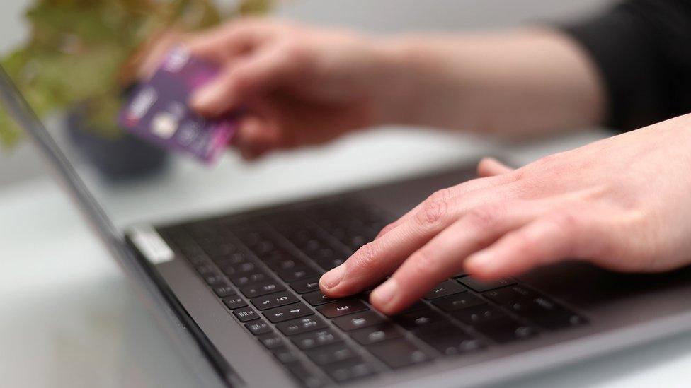 A woman using a laptop as she holds a bank card