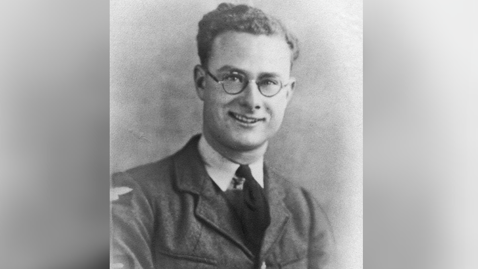 A black and white photo of a young man with glasses and short, curly hair wearing an RAF uniform - shirt, tie and jacket.