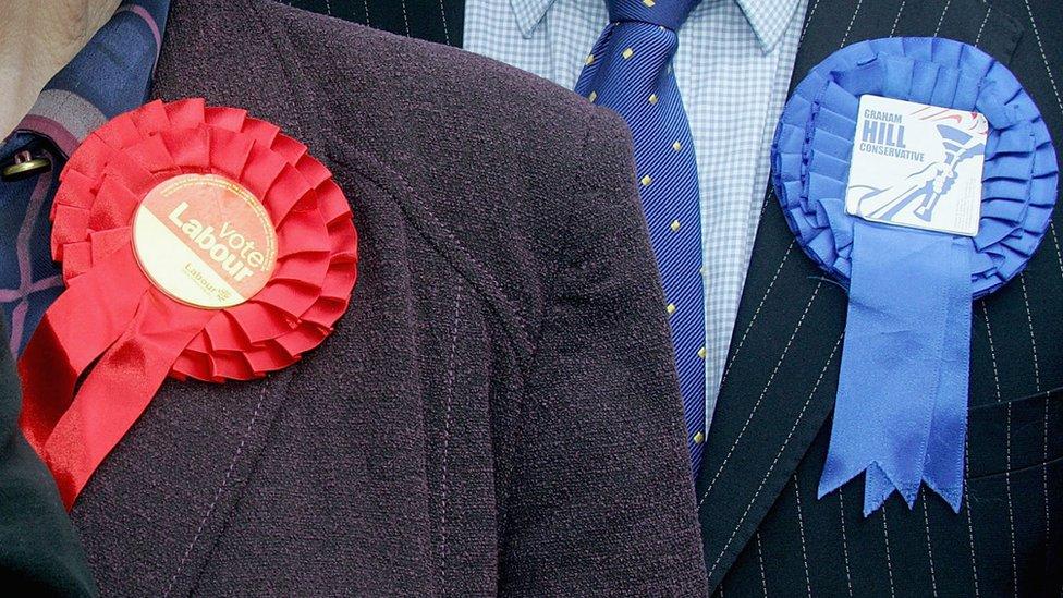 Election candidates wearing Labour and Conservative rosettes