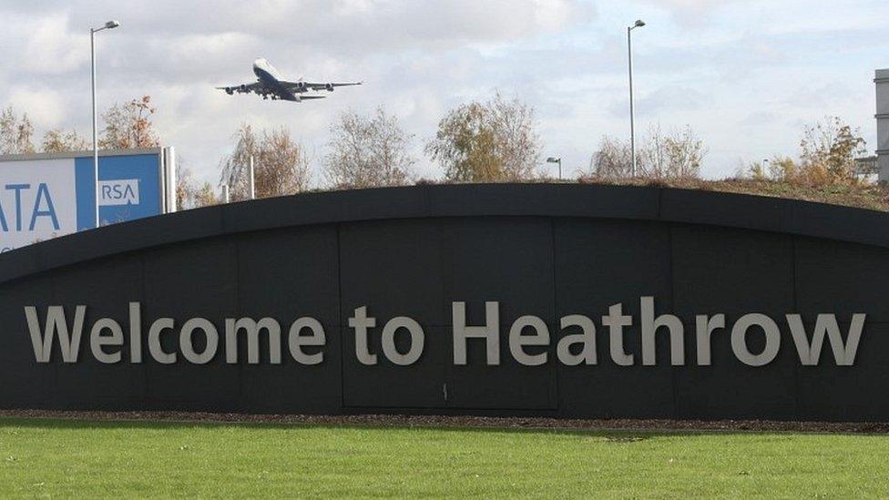 Plane flying above Heathrow Airport sign