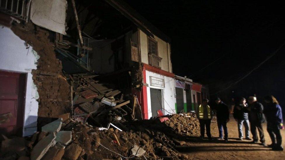 People stand outside a destroyed house in Illapel on 17 September, 2015.