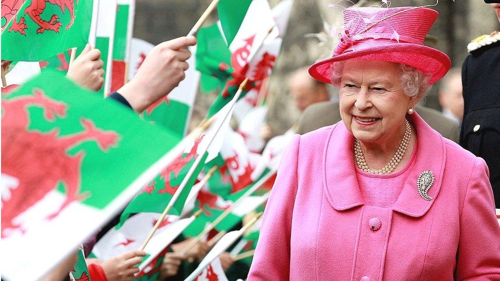 HM Queen Elizabeth II is cheered by school children with flags as she arrives at Caernarfon Castle on April 27, 2010