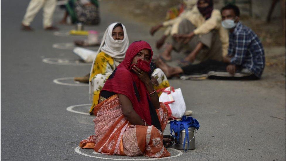 People waiting inside marked spots to maintain social distancing at a food distribution centre