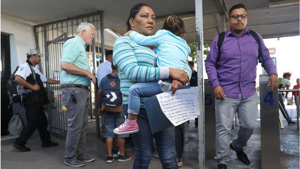 Migrant grandmother holds her granddaughter at the border, preparing to seek asylum