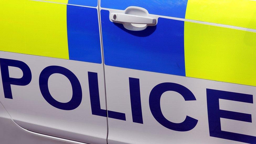 The side of a police vehicle with blue and yellow branding