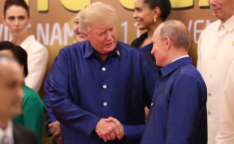 US President Donald Trump (L) shakes hands with Russia"s President Vladimir Putin (R) as they pose for a group photo