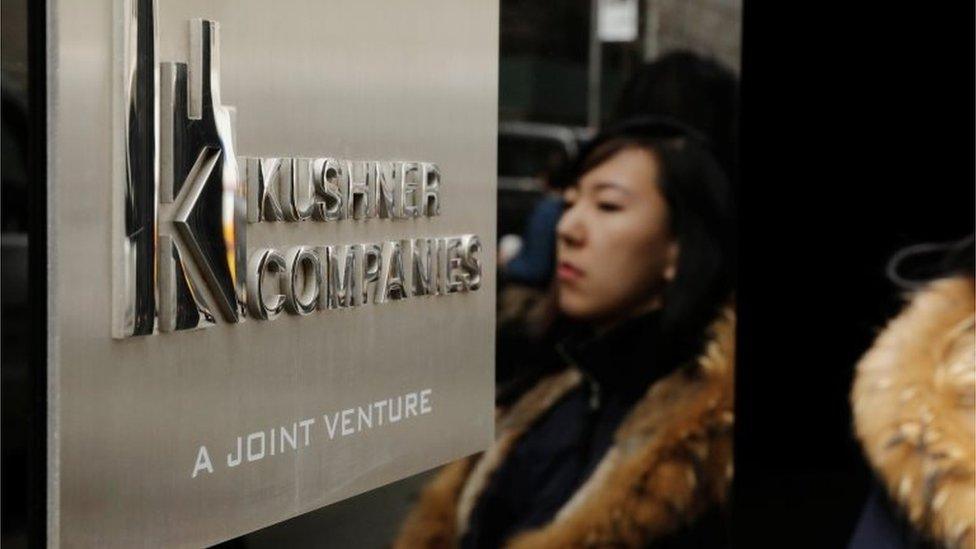 A woman is reflected next to a sign on the building at 666 Fifth Avenue, owned by Kushner Companies, in New York.