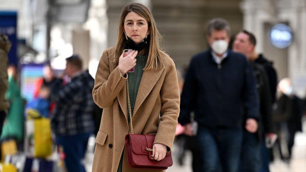 A woman takes off her mask at Waterloo station