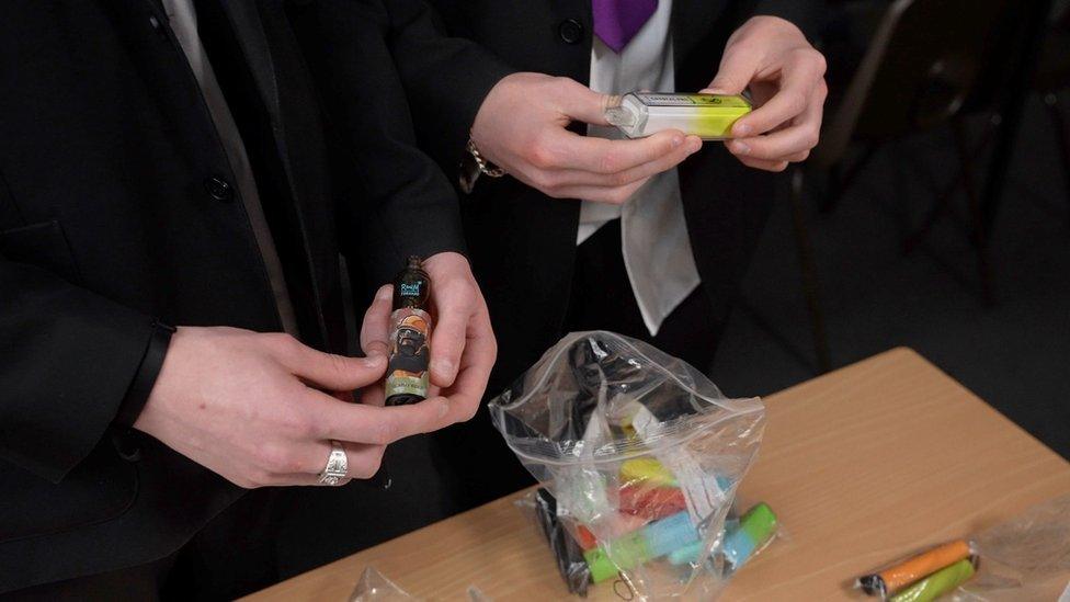 Teenagers hold some of the vapes confiscated at a secondary school