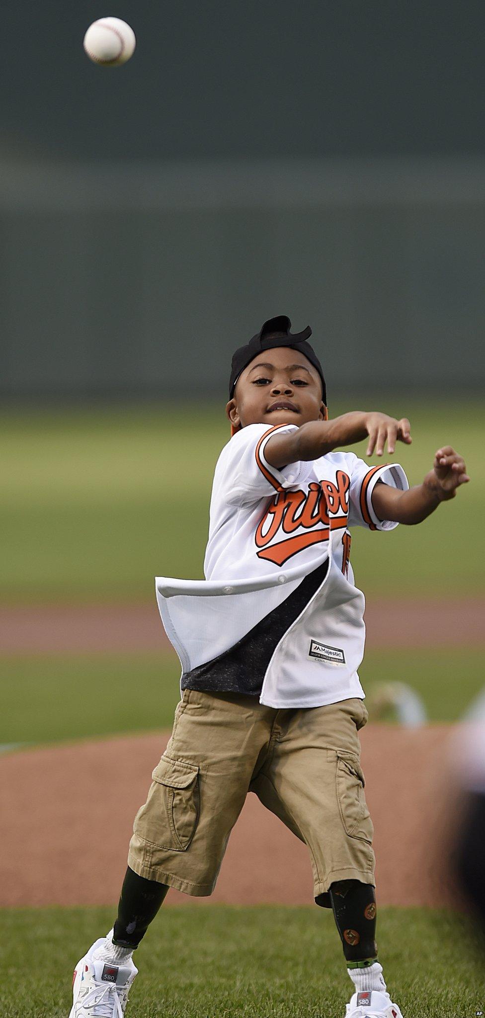 Zion Harvey throws out the first pitch before the Baltimore Orioles and Texas Rangers baseball in Baltimore.