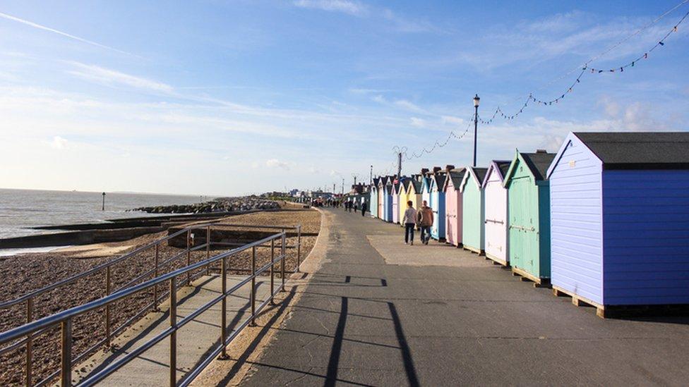 Promenade, with a drop to and on one side and beach huts on the other at Felixstowe beach.