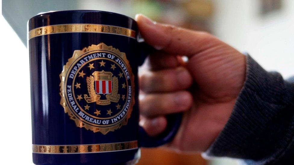 Man shows off an FBI coffee mug