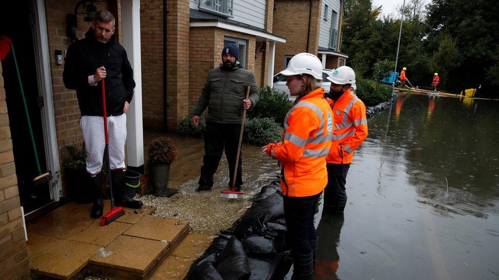 Water utilities workers talk with residents from flooded houses, in Hemel Hempstead, Herts on 4 October 2020