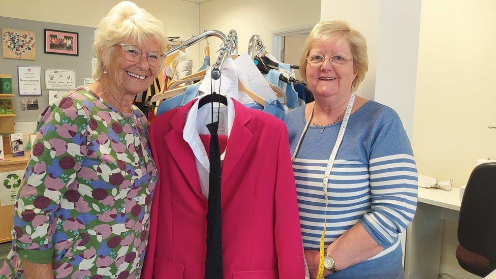 Edie Fox (left) and Anne Tuffin holding the pink suit between them