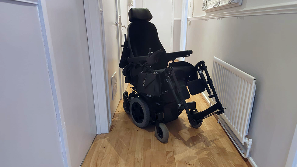 Image of Dr Lawson's powered wheelchair in the narrow hall