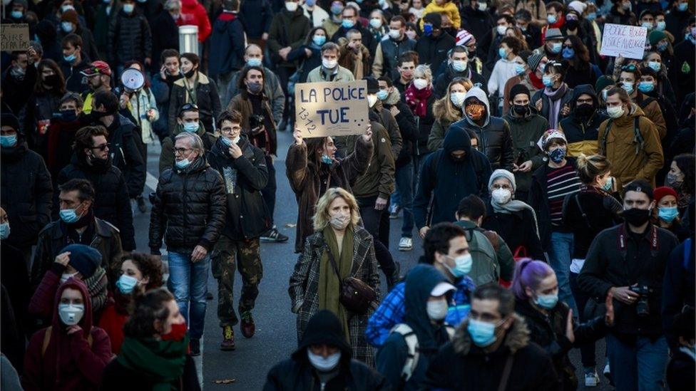 A protester holds a poster reading "The police kills" during a demonstration against a new security law, 28 November 2020