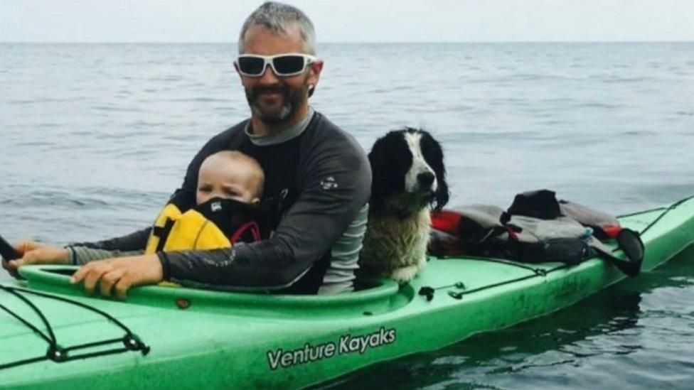 Kiara and Jet Moore with a dog, sitting in a kayak on the water