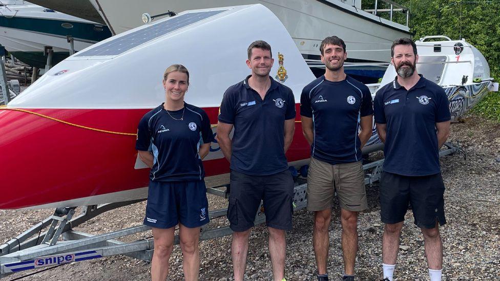 Jess Hunter, Dec Lynn, Gian-Luc Angiolini and Graham Doyle standing smiling in front of their boat. 