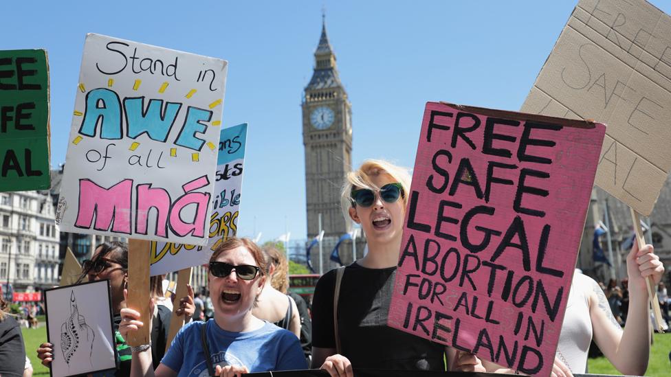 Protesters hold placards as they attend a demonstration against the Conservative party alliance with the DUP in Parliament Square on June 10, 2017