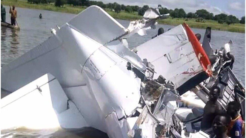 A handout image shows the wreckage of a light aircraft that crashed into the Yirol River as local fishermen use canoes to help in the rescue and retrieval efforts, 9 September 2018