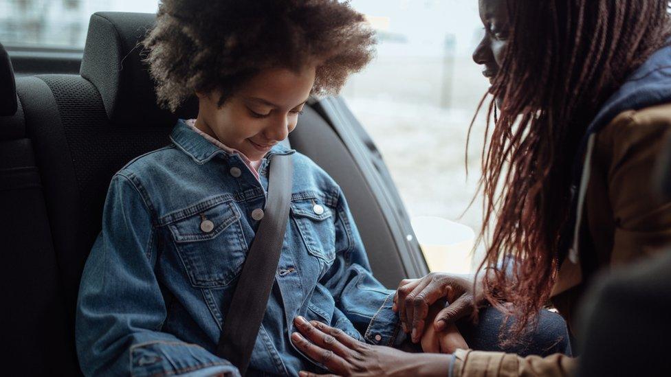 Child being buckled in with a seat belt