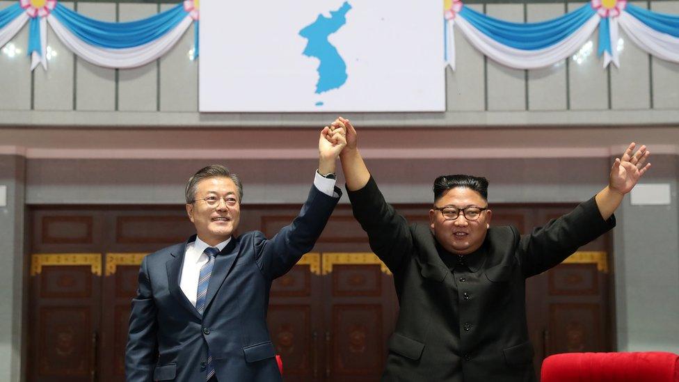 Moon Jae-in and Kim Jong-un raise held hands aloft