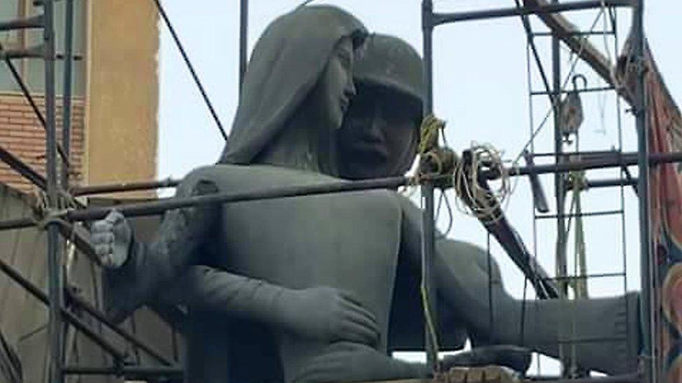 The Mother of the Martyr sculpture, which depicts a slender peasant woman, a traditional artistic representation of Egypt, with her arms outstretched with a helmeted soldier standing behind her, at a public square in Sohag, Egypt