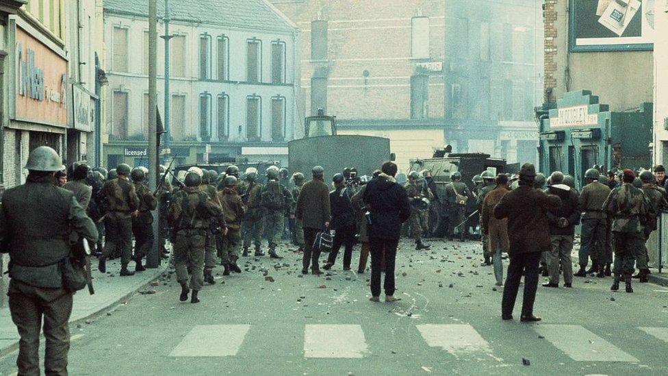 British soldiers and members of the press are pictured behind armoured water cannon and armoured cars as tensions rise during a civil rights march in Derry.