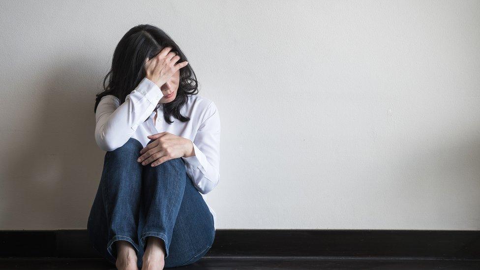 A woman sitting alone looking scared