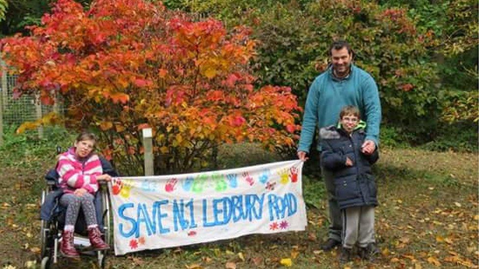 Gwen and Fergus and their father Ben holding a "Save No 1 Ledbury Road" banner