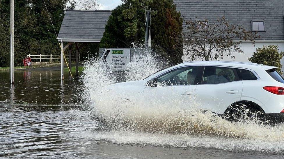 A white car makes its way through the flood waters in Purton, Wiltshire