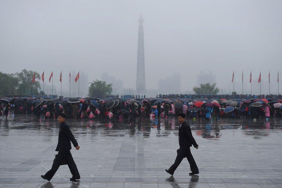 A crowd of people are seen on Kim Il-sung Square before the Juche tower as rain falls in Pyongyang on 6 May 2016.