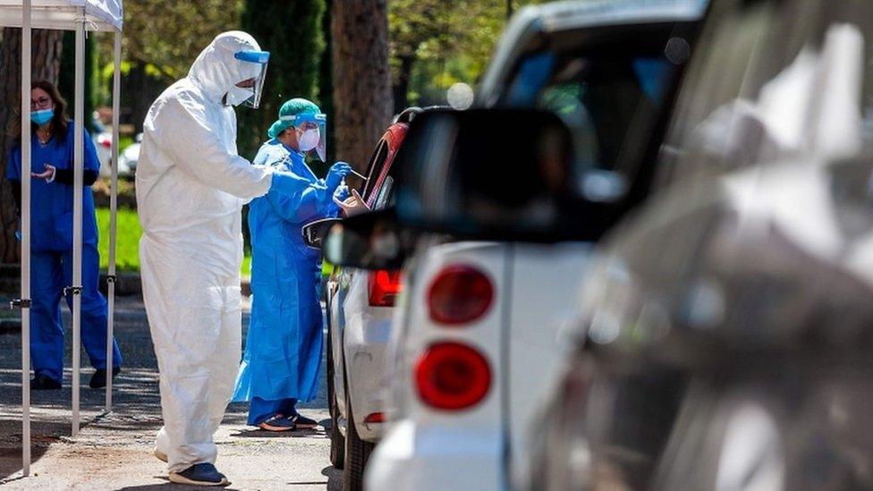 Medical workers perform swabs as drivers line up at a drive-through testing facility for COVID-19 in Rome