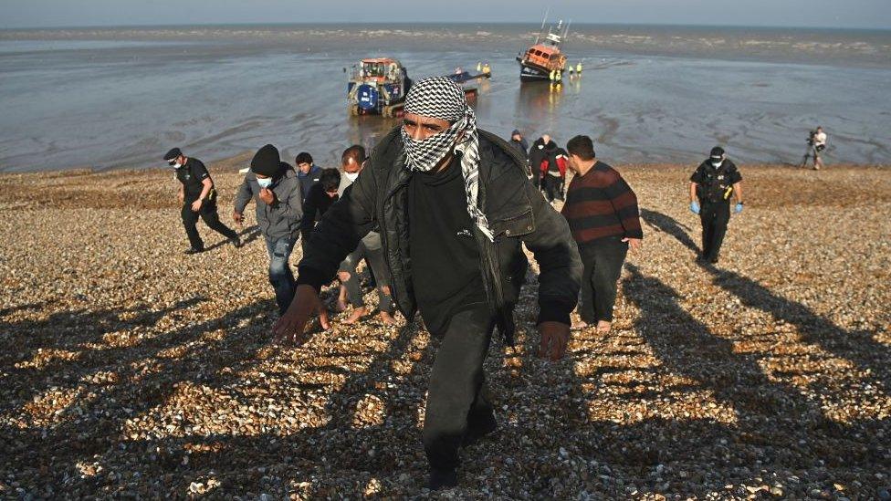 Migrants are escorted to be processed after being picked up by an RNLI boat and taken to shore at Dungeness