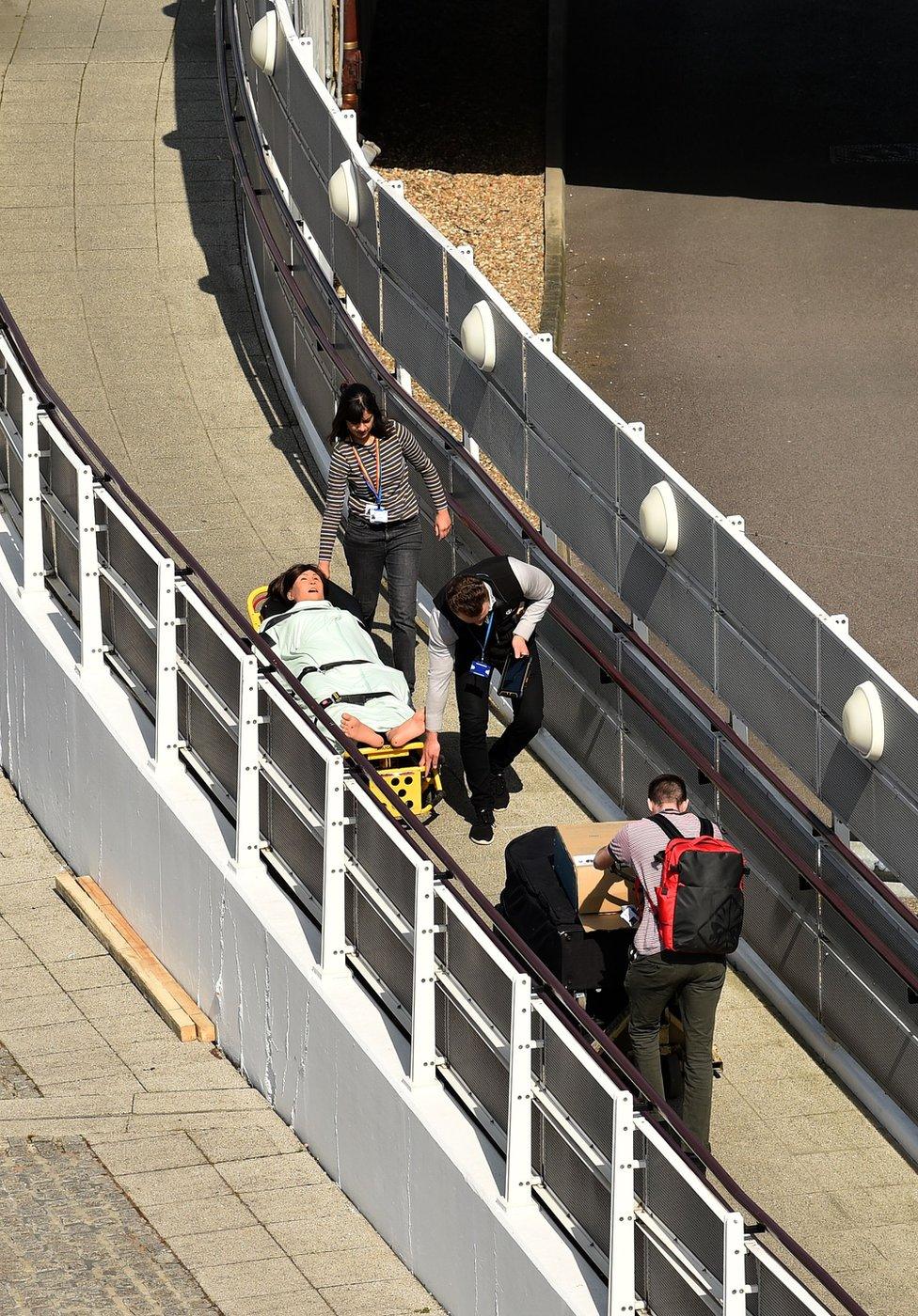 Medical staff move the dummy of a patient on a trolley