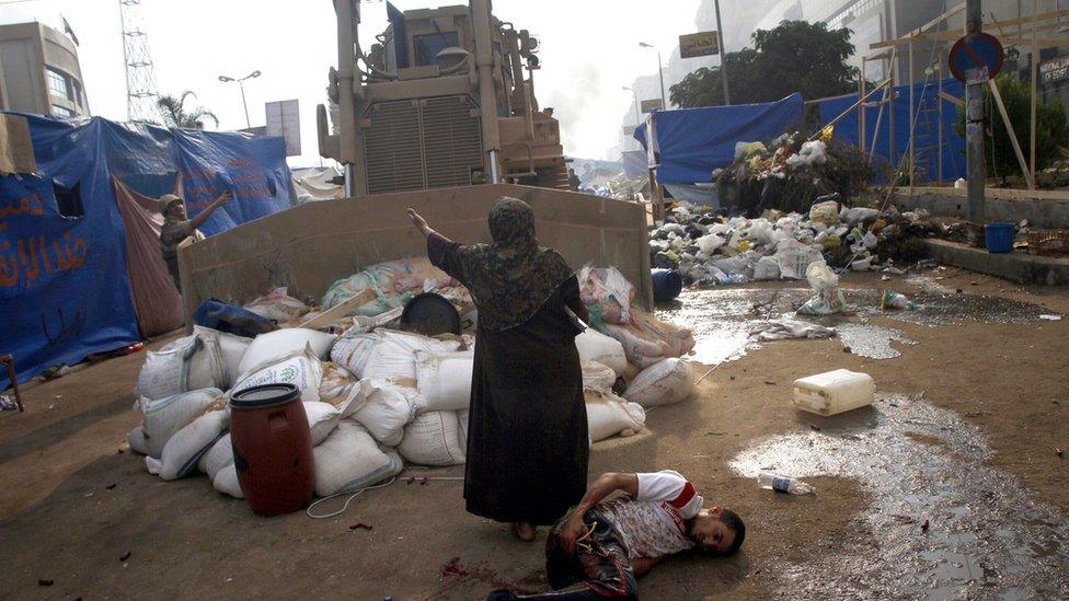 An Egyptian woman tries to stop a military bulldozer driving over a wounded youth at Rabaa al-Adawiya square, Cairo, on 14 August 2013